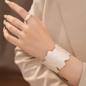 Detailansicht von unregelmäßigem geometrischem Ring und breitem Armreif-Set in Creme