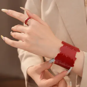 Nahaufnahme von rotem Emaille-Manschettenarmband und passendem Ring an der Hand der Frau.