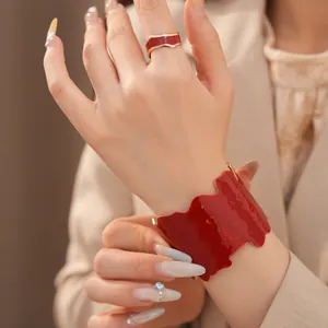 Nahaufnahme einer unregelmäßigen roten Emaille-Manschette und eines passenden Rings am Model.