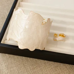 Nahaufnahme eines eleganten perlmuttweißen Armreifs und Rings mit unregelmäßiger Form