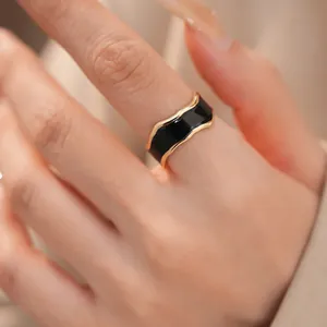 Detailansicht eines minimalistischen, gewellten Goldrings mit elegantem schwarzem Emaille-Finish