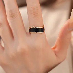 Nahaufnahme eines minimalistischen goldumrandeten Ringes mit schwarzem Emaille-Inlay.
