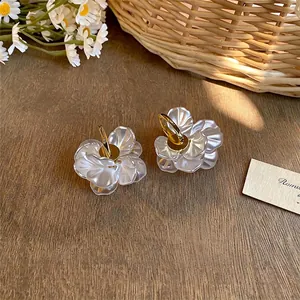 Elegant 14k gold-plated flower petal hoop earrings with pearl luster on wooden background