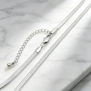 Detailed close-up view of a 3mm silver stainless steel flat blade chain on marble