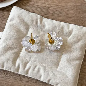 Vue détaillée de boucles d'oreilles pétales nacrés avec créoles plaquées or 14k sur coussin
