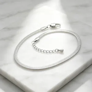 Macro view of a 3mm silver stainless steel flat snake blade chain bracelet on marble slab