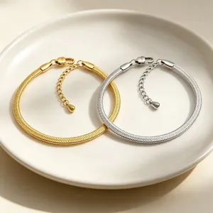 Detailed view of 3mm gold and silver stainless steel snake chain bracelets on a ceramic plate.