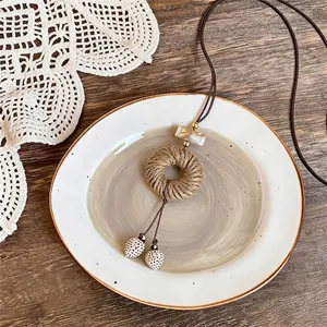 Collier bohème vintage fait main avec perles de coquillage sur une assiette blanche