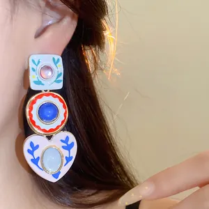 Close-up of colorful resin heart pendant earrings on model with asymmetric design details