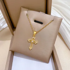 Détail d'un collier croix évidé doré en acier titane avec des pierres scintillantes