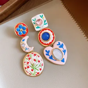 Close-up of asymmetric painted resin earrings with colorful floral and heart charms