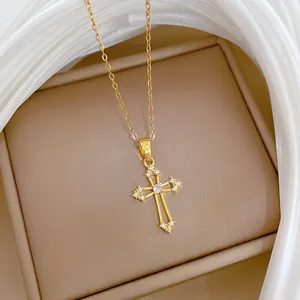 Gros plan d'un collier croix évidée en acier titane doré avec cristaux brillants.