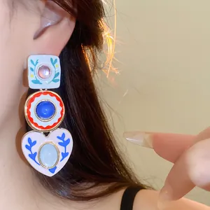 Close-up of asymmetric resin heart and circle earrings with floral patterns on model