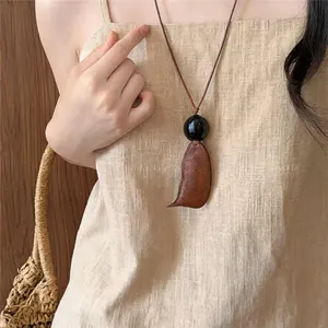 Primo piano di una collana retrò con pendente in legno e perla nera su abito di lino