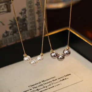 Detail of 18k gold plated necklace featuring three pearls in white and grey finishes