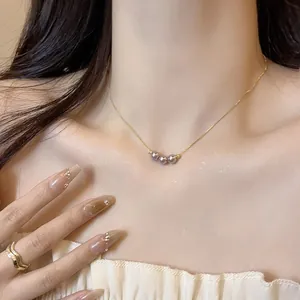 Elegant detail of an 18k gold plated clavicle chain featuring three dark lustrous pearls