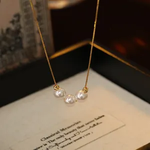 Macro view of 18k gold plated necklace featuring three elegant white pearls
