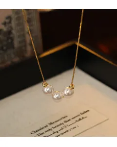 Close-up detail of 18k gold plated three-pearl pendant necklace on a delicate chain
