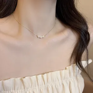 Detailed view of elegant 18k gold plated necklace with three dainty pearls on a model.