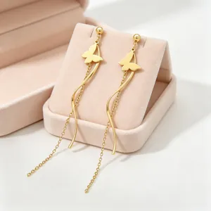 Élégantes boucles d'oreilles papillon dorées avec pampilles et détails ondulés dans un écrin