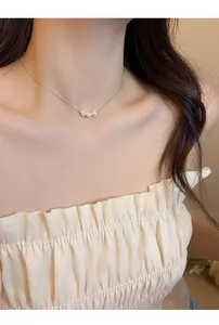 Elegant 18k gold plated necklace with three dainty pearls shown on a model's neckline.