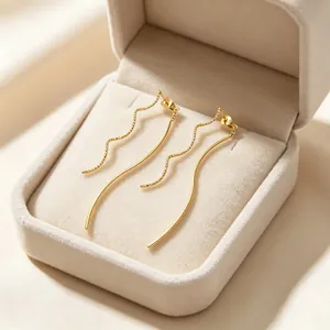 Gros plan de boucles d'oreilles dorées à fil ondulé dans un bel écrin en velours.