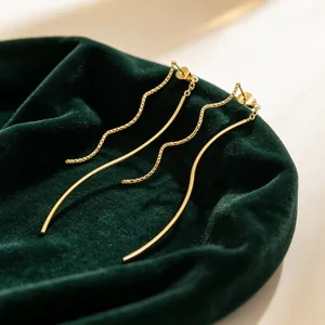 Vue détaillée de boucles d'oreilles dorées à pompons sur fond de velours vert