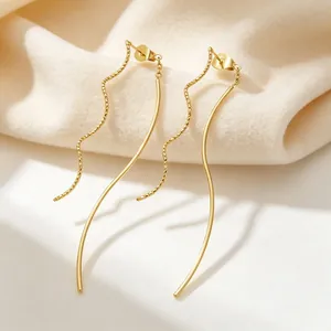 Gros plan sur des boucles d'oreilles dorées en forme de lignes ondulées aux finitions variées