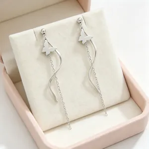 Détail de boucles d'oreilles argentées à pampilles avec papillon et lignes courbes