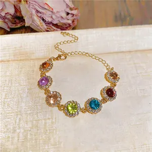Gros plan d'un bracelet doré avec des pierres précieuses arc-en-ciel et des strass