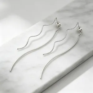 Gros plan de boucles d'oreilles en acier inoxydable avec lignes ondulées sur marbre