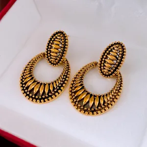 Nahaufnahme von vintage goldfarbenen ovalen Tropfenohrringen mit feinen Details