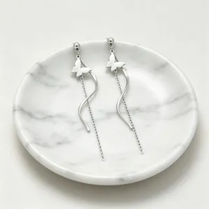 Vue détaillée de boucles d'oreilles papillon argentées avec pompons et lignes