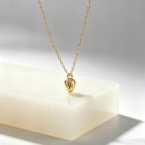 Nahaufnahme eines minimalistischen goldenen Blumenknospen-Anhängers aus Edelstahl.