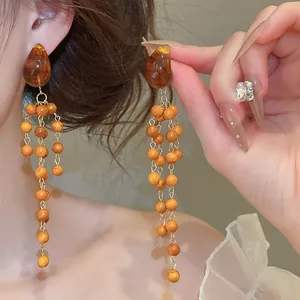 Close-up of vintage Maillard style long drop earrings with wood beads and amber crystal