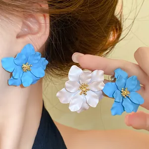 Detaillierte Nahaufnahme eleganter französischer blau-weißer Blumenohrstecker am Ohr