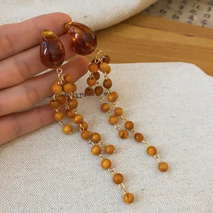 Detailed view of vintage wood beaded earrings in warm Maillard brown tones.