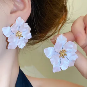 Detailansicht großer weißer Blumenohrstecker mit goldener Mitte am Ohr des Models