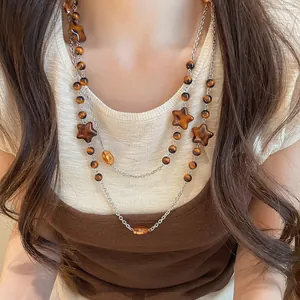 Detail shot of a vintage amber-colored beaded necklace with stars on a model's neck.