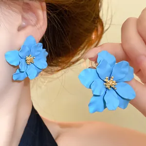 Detailansicht der matten blauen Blumenohrstecker mit goldener strukturierter Mitte