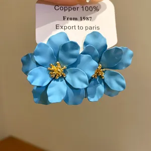 Detailansicht blaue matte Blumenohrringe mit goldfarbener Mitte auf weißer Displaykarte