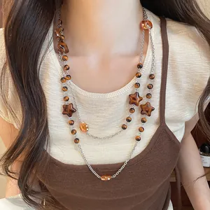 Detail view of vintage Maillard brown beads and star crystal sweater chain worn by model