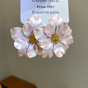 Elegante blassrosa Blumenohrstecker mit goldenem Staubblatt auf weißer Displaykarte
