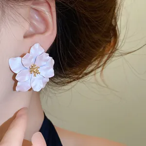 Detailaufnahme eines großen weißen Blumenohrsteckers am Ohr eines weiblichen Models