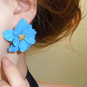 Detaillierte Makroansicht eines großen blauen mattierten Blumenohrrings mit goldenem Kern