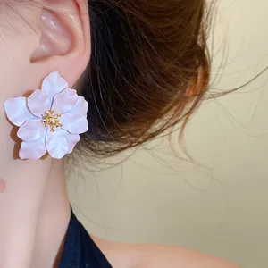 Detailansicht eleganter mattweißer Blumenohrringe an einem Model, süßer französischer Stil.