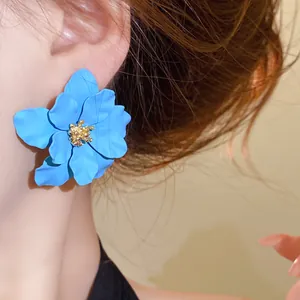 Nahaufnahme eines eleganten, hellblauen, matten Blumenohrrings, der von einem Model getragen wird