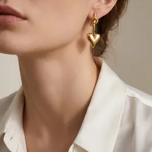 Fashionable gold stainless steel knot with 3D heart dangle earrings worn by a female model