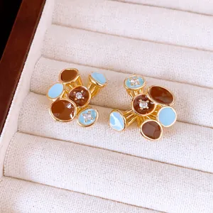 Detailweergave van 18k vergulde bloem oorknopjes met bruin en blauw emaille lak