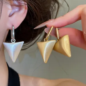 Close-up van elegante goud- en zilverkleurige geometrische driehoekige oorbellen